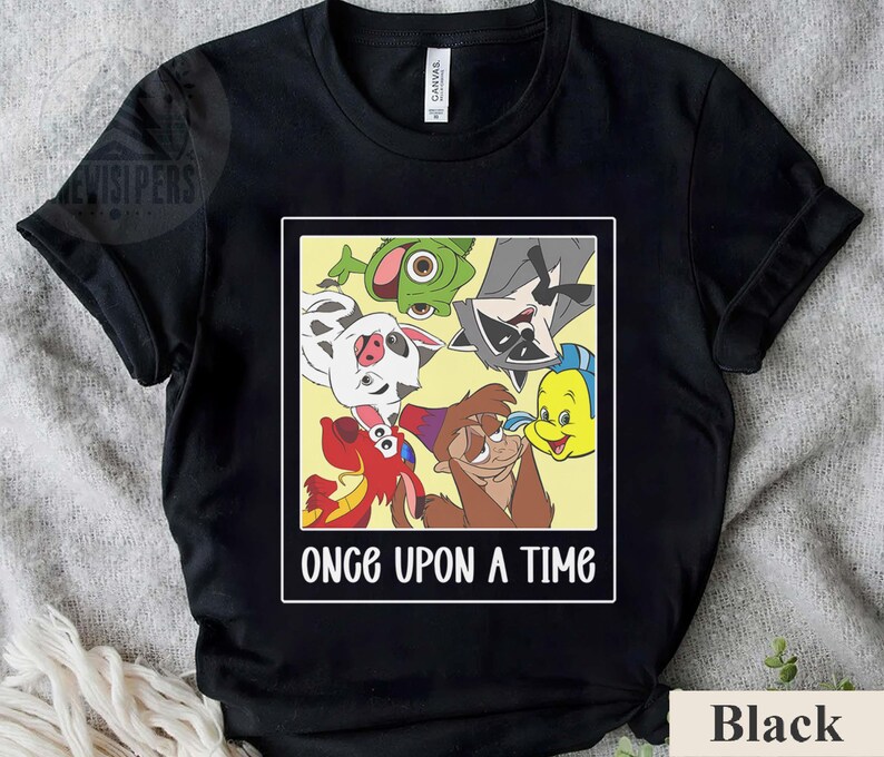 Op de afbeelding: Zwart T-shirt met een rechthoekige afbeelding met tekenfilmfiguren en de tekst "ONCE UPON A TIME" in het wit. De afbeelding bevat een Dalmatische hond, een wasbeer en andere geanimeerde figuren.