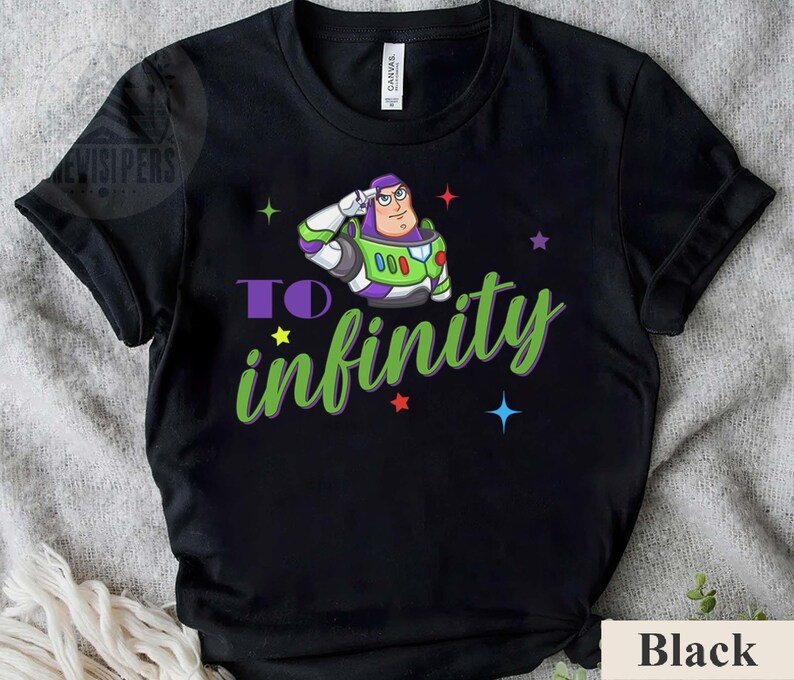May include: Black t-shirt featuring a cartoon image of Buzz Lightyear saluting, with the words "TO infinity" in green and purple. The design includes colorful stars. The shirt is made of a soft material.