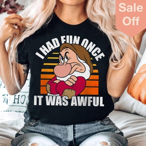 May include: A black t-shirt featuring a retro-style graphic of Grumpy from Snow White. The graphic shows Grumpy with his arms crossed and the text "I had fun once it was awful".