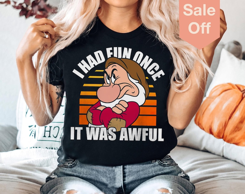 May include: A black t-shirt featuring a retro-style graphic of Grumpy from Snow White. The graphic shows Grumpy with his arms crossed and the text "I had fun once it was awful".