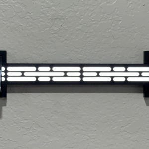 Puede incluir: Decoraci&oacute;n de pared negra con una serie de luces blancas rectangulares horizontales. Las luces est&aacute;n dispuestas en un patr&oacute;n a trav&eacute;s de una barra rectangular negra. La decoraci&oacute;n est&aacute; montada en una pared gris claro con soportes negros.