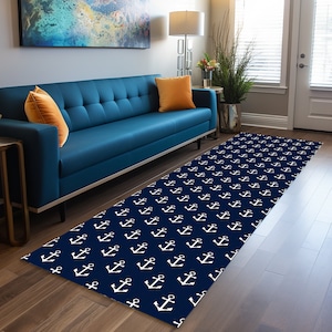 May include: A navy blue runner rug with a white anchor pattern. The rug is placed in front of a blue sofa with orange throw pillows.