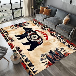 May include: A beige area rug with a black bear silhouette in the center. The bear is surrounded by a colorful geometric pattern with red, blue, and black accents. The rug has a tribal design with a southwestern theme.