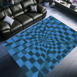 May include: A blue geometric patterned rug with a 3D cube design. The rug features shades of blue, creating a visually striking optical illusion. The rug is rectangular and placed on a wooden floor.