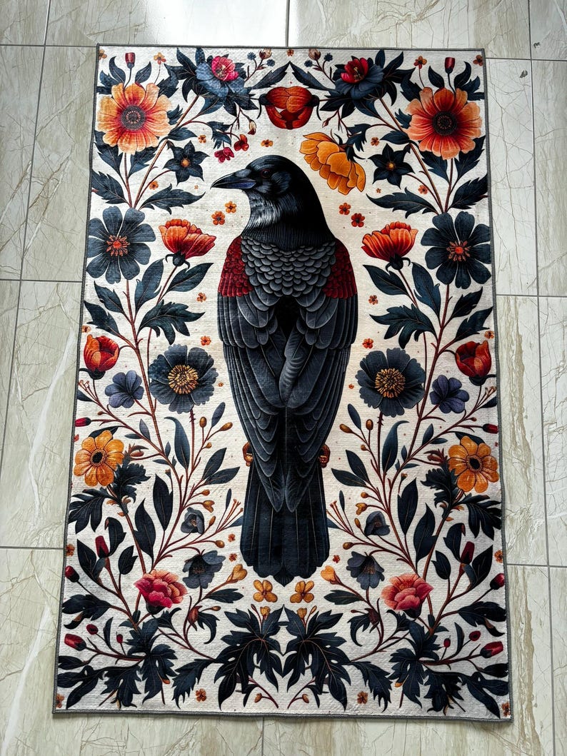 May include: A black raven with a red breast is depicted in the center of a white rug with a floral pattern. The flowers are in shades of red, orange, yellow, and blue.