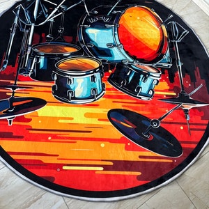 May include: Round area rug featuring a stylized drum kit illustration. The design includes drums, cymbals, and stands set against a fiery orange and red background, with a black border. The rug is suitable for a music room or a living space.