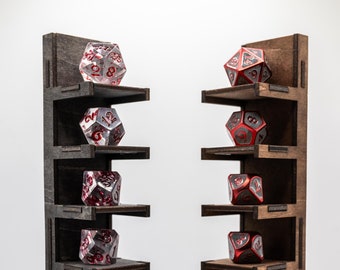 May include: Two wooden dice display shelves, each with multiple levels, showcasing various polyhedral dice. The dice are clear with red numbering and solid red with silver numbering. The shelves are dark brown.