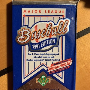 May include: A sealed 1991 Upper Deck baseball card pack. The blue and silver packaging features the words "MAJOR LEAGUE Baseball" and "1991 EDITION." It includes details about the contents, such as 15 baseball cards and a 3-D team logo hologram.