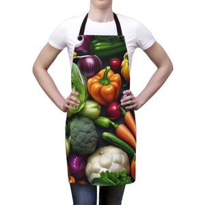 May include: An apron featuring a vibrant, colorful vegetable pattern. The design includes a variety of produce such as orange bell peppers, red onions, green broccoli, and carrots. The apron has a black neck strap and is worn by a person.