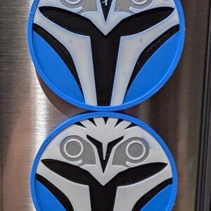 May include: Two round blue, white, and black Mandalorian helmet magnets. The magnets are approximately 3 inches in diameter.