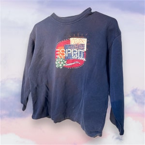 Può includere: Felpa blu navy con la scritta "ESPRIT" in un cerchio rosso e bianco. La felpa ha un girocollo e maniche lunghe. La grafica include anche le parole "de corp."
