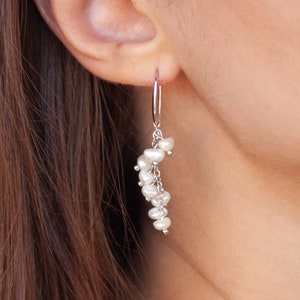 Puede incluir: Pendientes de aro de plata con un racimo de perlas blancas que cuelgan de la parte inferior.