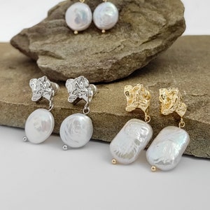 May include: Two pairs of gold and silver earrings with pearl drops. The earrings feature a textured, geometric design.