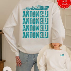 Pu&ograve; includere: Una felpa bianca a maniche lunghe con una grafica color verde acqua di un'auto da corsa e il testo ANTONELLI ripetuto sul retro. La parte anteriore della felpa mostra il numero 12 in verde acqua sul petto a sinistra, visibile in un riquadro.