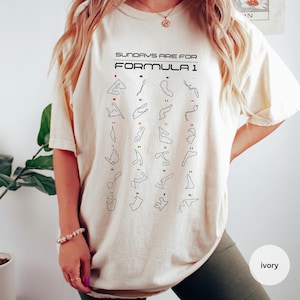 May include: Ivory t-shirt with the text "SUNDAYS ARE FOR FORMULA 1" in black. The shirt displays a grid of Formula 1 race track outlines with coloured accents. The t-shirt has a relaxed fit.