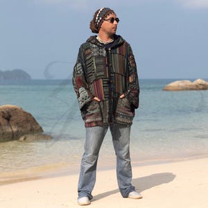 May include: A multi-colored patchwork hooded jacket with a button closure. The jacket has a variety of patterns and textures, including stripes, geometric designs, and floral motifs. The model is wearing the jacket with blue jeans and a headband.