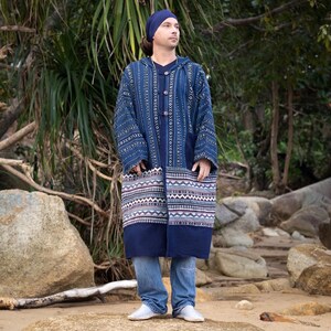 May include: A long, blue, hooded jacket with a geometric pattern. The jacket has a button closure and a white trim around the bottom hem. The jacket is made of a soft, comfortable fabric.