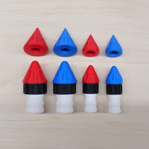 May include: Set of nine red and blue plastic rocket-shaped nozzle tips. The tips are different sizes and have a black ring around the base.
