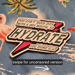 May include: A rectangular embroidered patch with a jagged lightning bolt shape in red and black. The text reads: YOU CAN'T SUCK [censored] WITH A DRY MOUTH, SO HYDRATE YOU DUMB [censored]. The patch features white, green, red, and black thread colours.