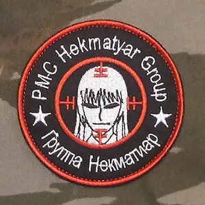 May include: Round embroidered patch with the text "PMC Hekmatyar Group" in white and Russian text. The patch features a stylized face within a red target design, surrounded by a black border and a camouflage background.