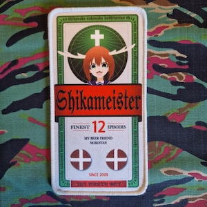 Könnte beinhalten: Ein weißer Patch mit einem rot-weißen Design. Der Patch zeigt eine Comicfigur mit Geweih, einem Kreuz und dem Text "Shikameister", "Finest 12 Episodes", "My Beer Friend Nokotan", "Since 2009" und "143yE BORSAIN ROT".