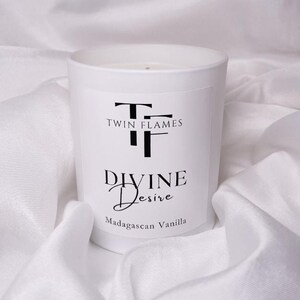May include: White candle with a black label that reads "Twin Flames Divine Desire Madagascan Vanilla"