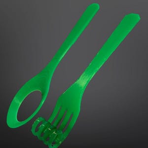 May include: Bright green spoon and fork set. The spoon has a circular opening in the bowl. The fork features a spiral design at the base of the tines. Both utensils are made of a solid, smooth material and are set against a dark gray background.