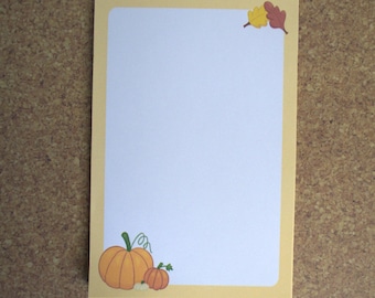 May include: A blank card with a yellow border and a fall theme. The card features two orange pumpkins and two fall leaves in the top right corner.