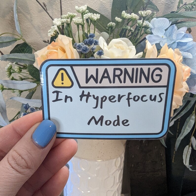 以下が含まれることがあります： 「WARNING In Hyperfocus Mode」と書かれた青と黄色の警告ステッカーです。