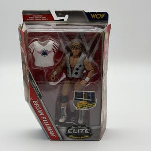 May include: A Brian Pillman action figure in a clear plastic package. The figure is wearing a gray vest with black stars and red trunks. The package includes a Steve Austin vest and a Randy Savage shirt. The package also has the text "WCW" and "ELITE".