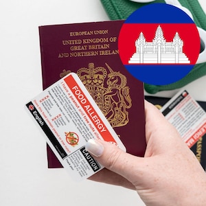 以下が含まれることがあります： 赤と白で「食物アレルギー」と書かれた食品アレルギーカードが付いた、バーガンディ色のパスポート。カードには、その人がピーナッツとナッツにアレルギーがあることが記載されています。背景にはカンボジアの国旗があります。