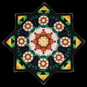 May include: A colorful, geometric textile design with a central floral pattern in orange, white, and yellow. The design is surrounded by a black border with green and orange accents. The text "trippysquid.com" is visible.