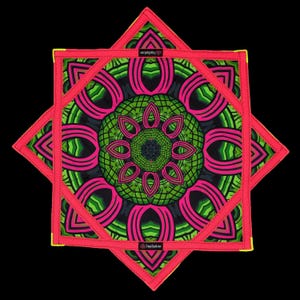 May include: A square fabric mat featuring a vibrant mandala pattern in neon pink, lime green, and black. The edges are finished with bright pink stitching and yellow corner accents. A small black label with the text TrippySquid is visible.