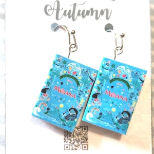 May include: A pair of square earrings featuring a blue design with the word "MOANA" in red. The earrings have silver-colored hooks and are displayed on a white card with the text "All Things Autumn".