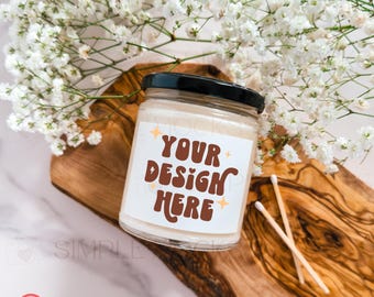 May include: A clear glass candle jar with a black lid and a white label that says "YOUR DESIGN HERE" in brown letters with yellow stars. The candle jar is sitting on a wooden cutting board with two wooden matches.