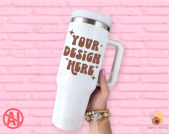 Puede incluir: Vaso térmico blanco con asa y tapa, con el texto "YOUR DESIGN HERE" en marrón. El vaso se sostiene sobre un fondo rosa. El vaso está diseñado para contener aproximadamente 887 ml.
