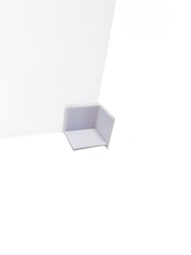 May include: White plastic corner protector with a smooth surface.