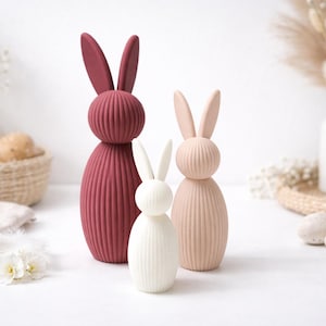 Pu&ograve; includere: Tre statuette decorative a forma di coniglio di diverse dimensioni e colori. Il pi&ugrave; grande &egrave; rosso scuro, quello centrale rosa chiaro e il pi&ugrave; piccolo bianco. Tutti hanno una texture a coste e lunghe orecchie, perfetti per Pasqua.