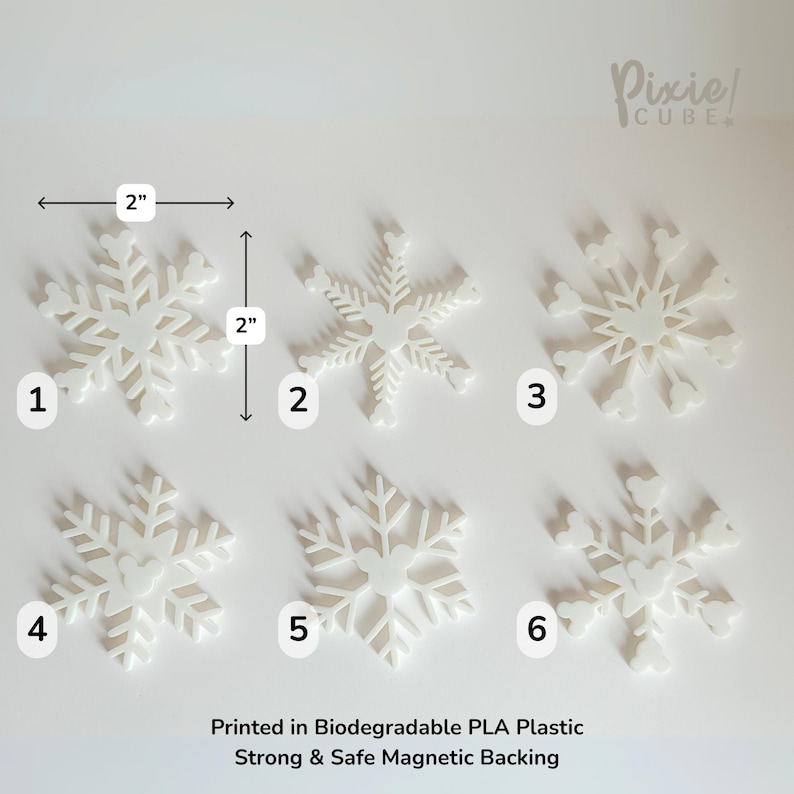 May include: Six white snowflake-shaped ornaments, each approximately 2 inches in diameter, are displayed on a white surface. The ornaments are numbered 1 through 6. The text "Printed in Biodegradable PLA Plastic Strong & Safe Magnetic Backing" is visible.