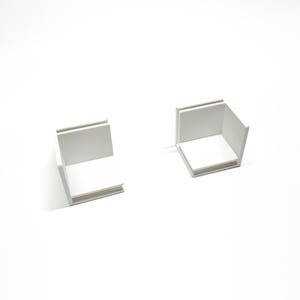 May include: Two white cardboard boxes with open tops, sitting on a white surface.
