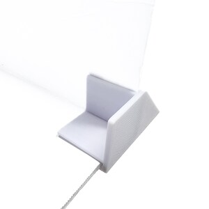May include: White plastic desk divider stand with a clear plastic panel. The stand has a white string attached to it.