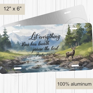May include: A 12-inch by 6-inch aluminum license plate featuring a scenic landscape with a river, mountains, and a deer. The text "Let everything that has breath praise the Lord Psalm 150:6" is printed in black on the plate.