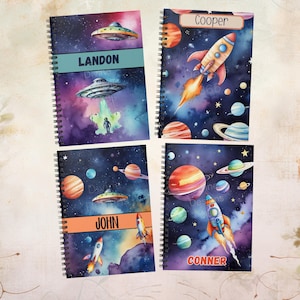 May include: Four spiral-bound notebooks with space-themed designs. Each notebook features a unique outer space illustration with planets, rockets, and UFOs. The notebooks are personalized with names: Landon, Cooper, John, and Conner.