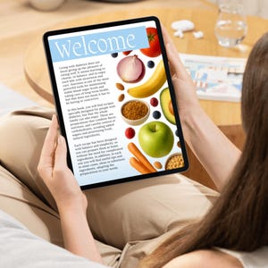 May include: A tablet displaying a recipe book with the title "Welcome." The screen features colorful images of fruits and vegetables, including a tomato, onion, banana, and avocado. The text discusses diabetes-friendly recipes.
