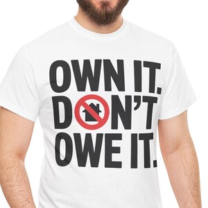 Può includere: Una maglietta bianca con la scritta "OWN IT. DON'T OWE IT." in grassetto nero. La parola "DON'T" presenta un cerchio rosso con un simbolo di casa sbarrato. La persona indossa jeans blu.