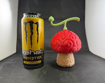 May include: A red and white 3D printed mushroom with a green stem. The mushroom is about 5 inches tall and is sitting on a black surface. The mushroom is a replica of the "Hito Hito no Mi" Devil Fruit from the anime series "One Piece".