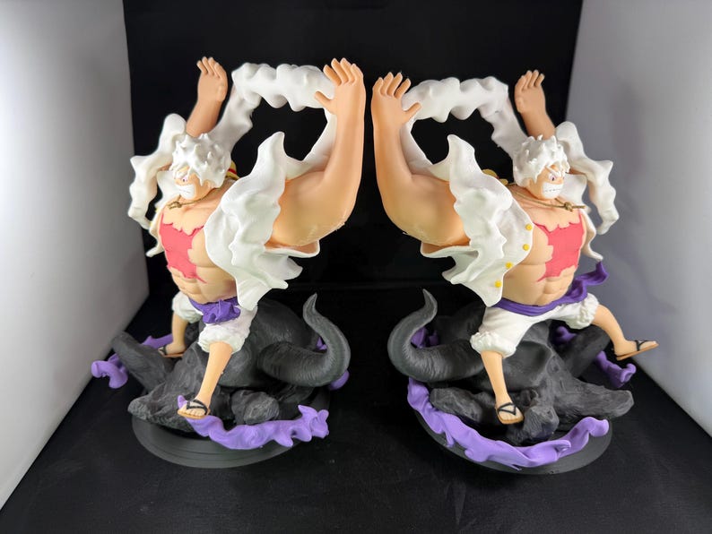 May include: A white and red figurine of a character with white hair and a white shirt. The character is standing on a black and purple base. The figurine is a popular anime character.