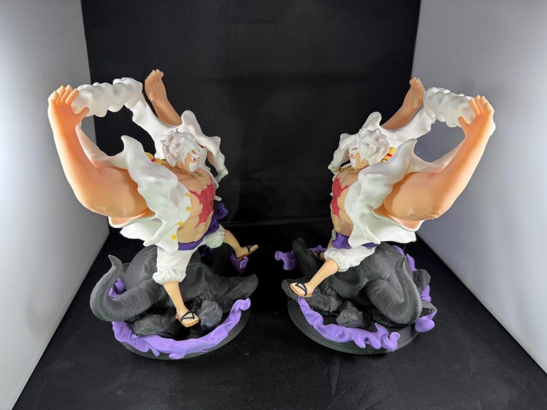 May include: Two white and red anime figurines with white hair and black and purple bases. The figurines are posed with their arms raised and their hands holding white clouds.