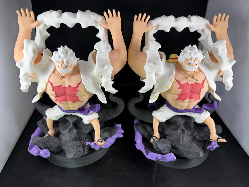 May include: Two white and red anime figurines with white hair and black and purple bases. The figurines are holding white fabric in their hands.
