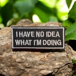 Puede incluir: Parche bordado en blanco y negro con el texto "No tengo ni idea de lo que estoy haciendo".